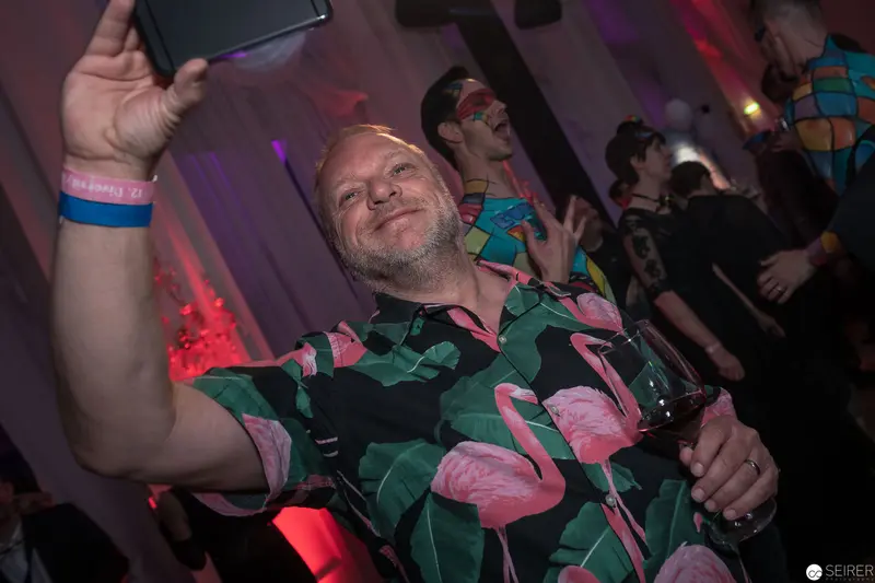 Festive Nightlife Scene with Smiling Participant in Flamingo-Print Shirt