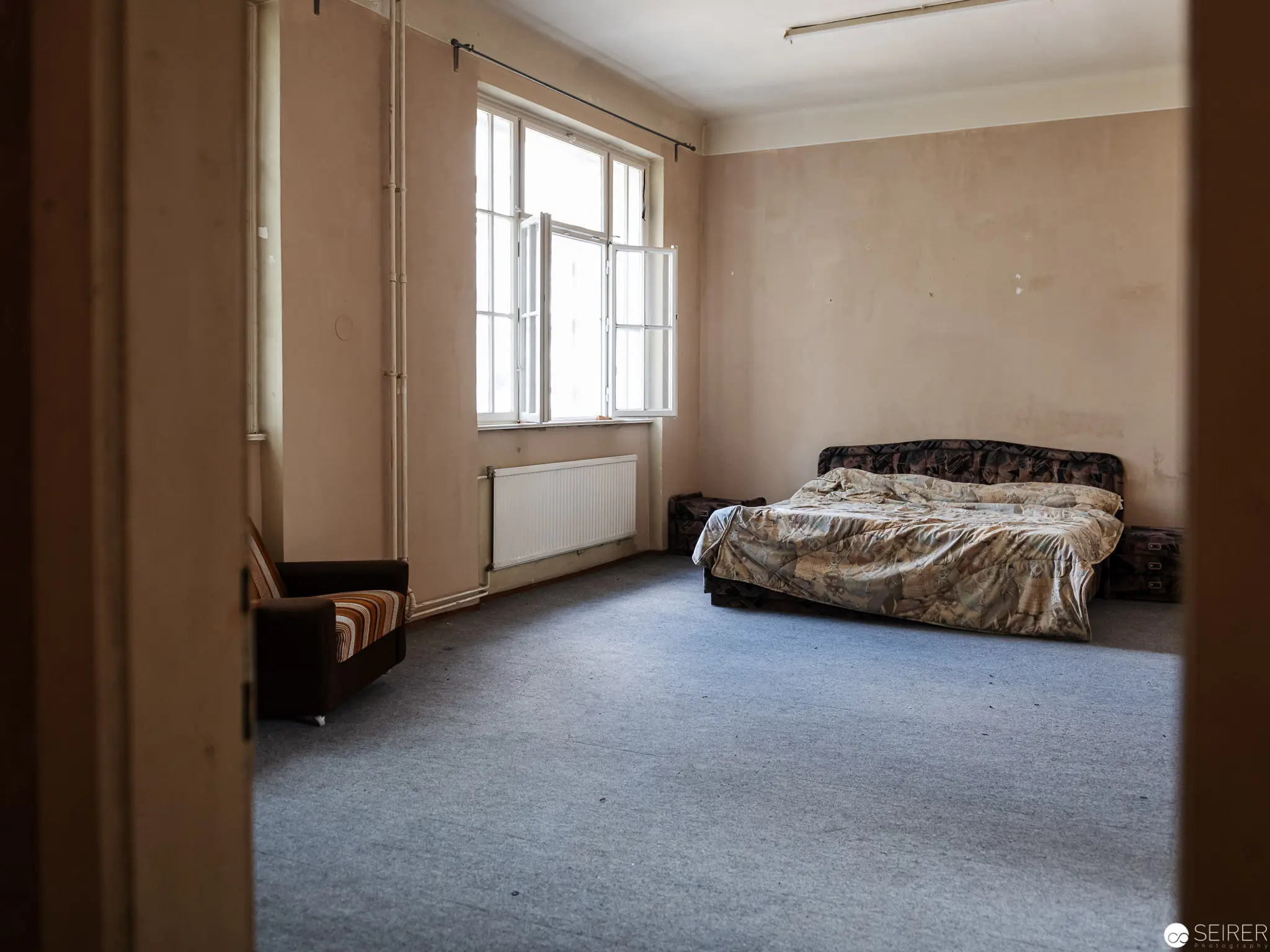Empty Interior Study: Minimalist Bedroom with Rumpled Bedding and Gray Carpet