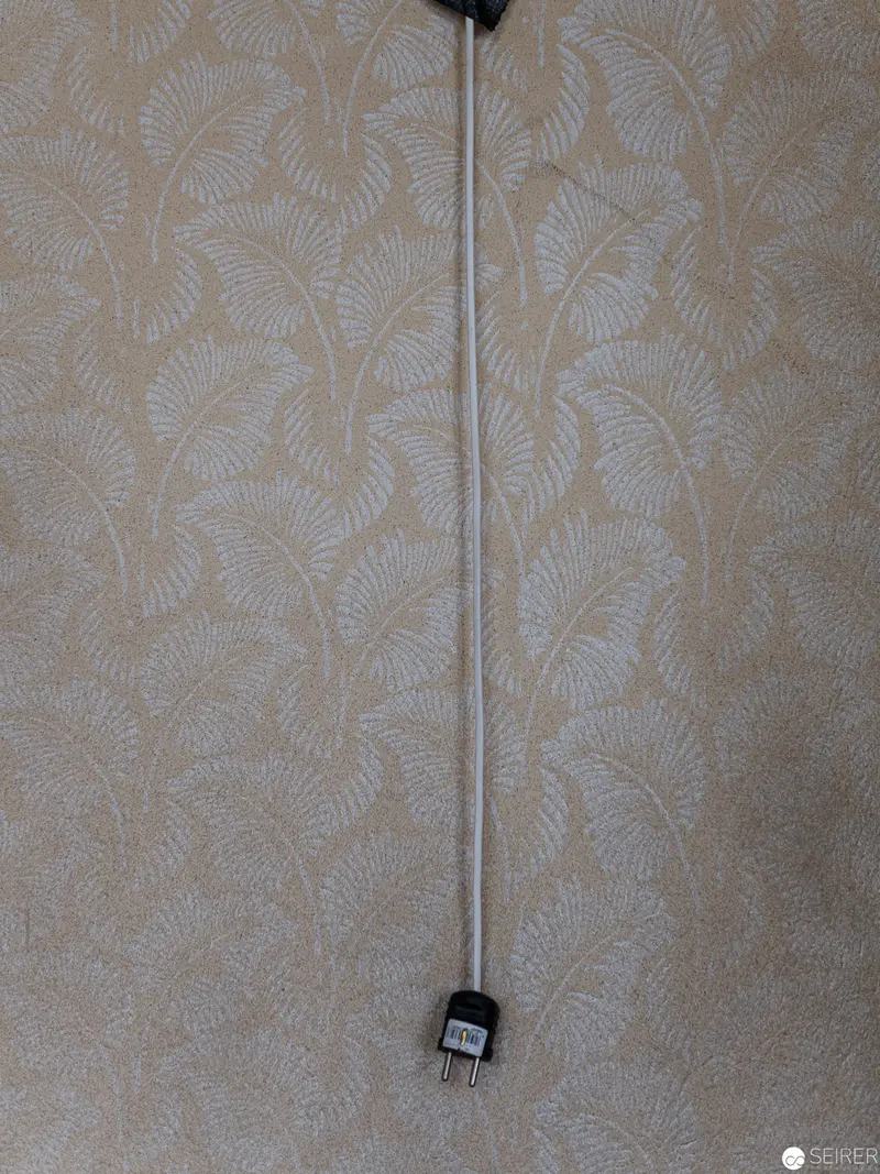 Electrical Cord Suspended Against Delicate Botanical Wallpaper Pattern