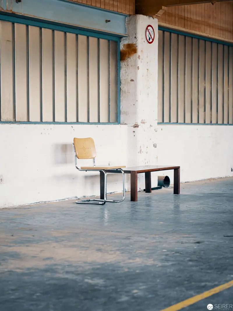 Minimalist Interior Study: Solitary Chair and Table in Industrial Space