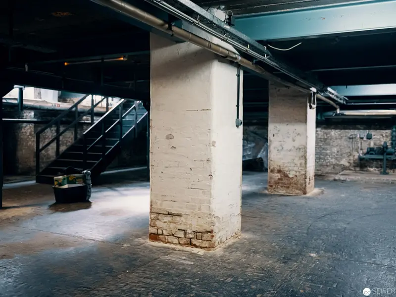 Industrial Basement Interior with Exposed Brick Pillar and Metallic Infrastructure