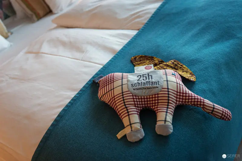 Checkered Plush Figure Resting on Teal and White Bedding