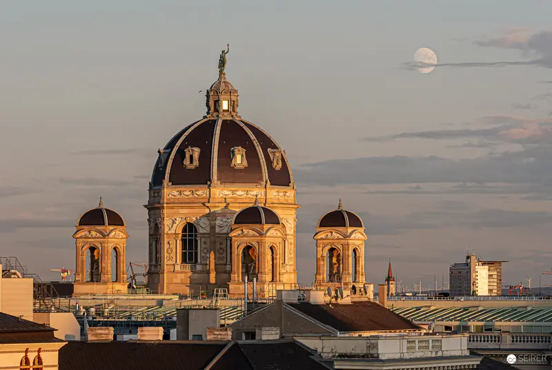 Golden-Hued Baroque Dome at Sunset with Full Moon Over Urban Cityscape