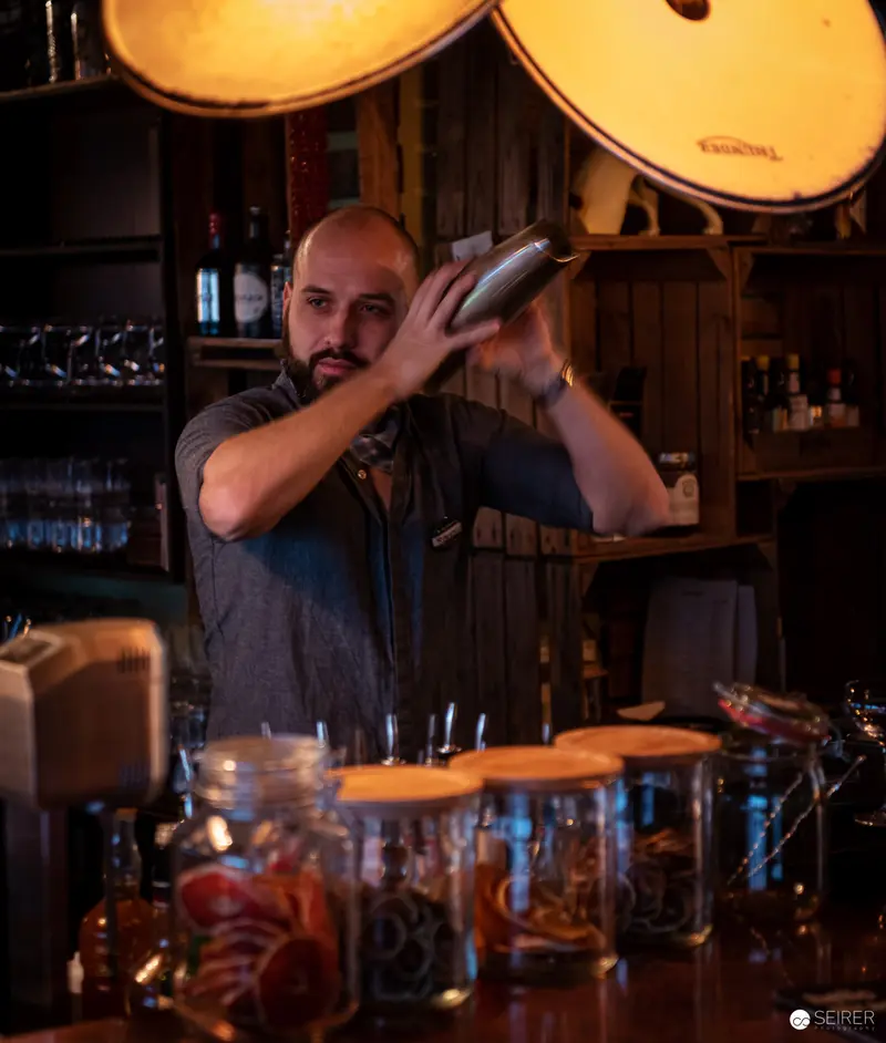 Mixologist Preparing Cocktail Under Warm Ambient Bar Lighting