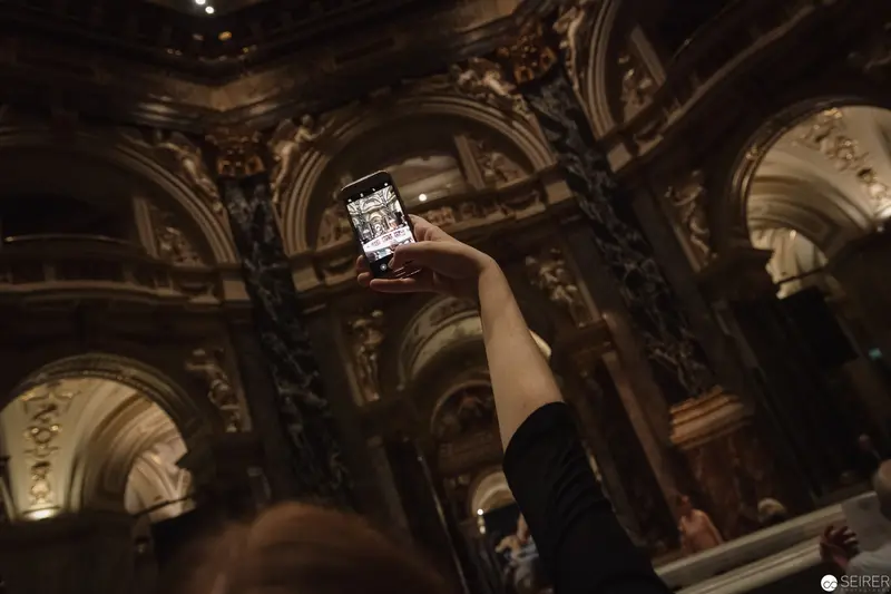 Hand Holding Smartphone Amidst Baroque Architectural Splendor at Caravaggio & Bernini Exhibition