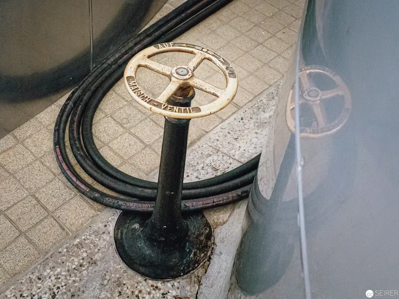 Vintage Industrial Valve Wheel with Coiled Cables on Tiled Floor