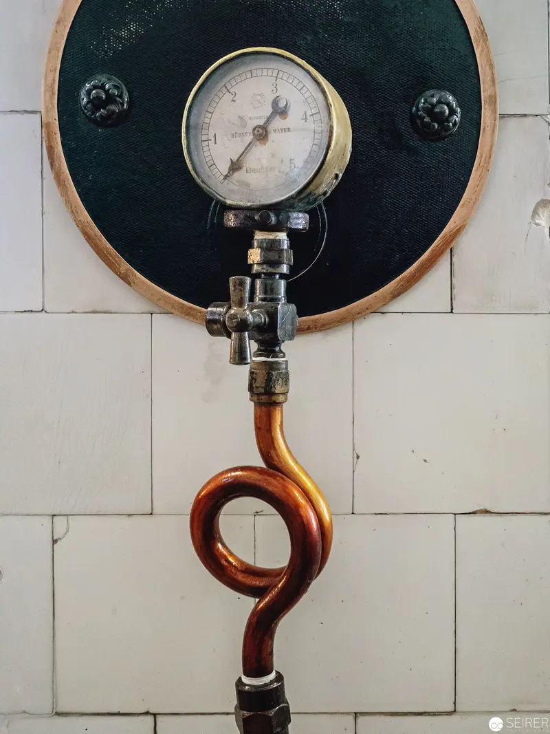 Industrial Pressure Gauge with Curved Copper Pipe on Tiled Wall