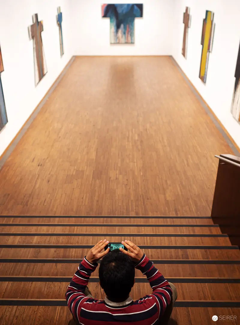 Contemplative Viewer in Striped Shirt Observing Art Gallery Perspective