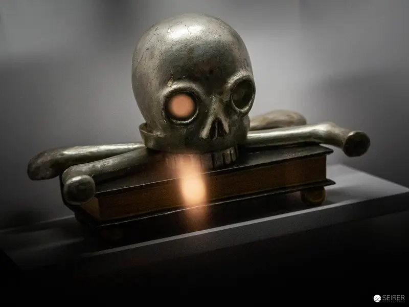 Metallic Skull Sculpture Illuminated on Vintage Book with Dramatic Lighting
