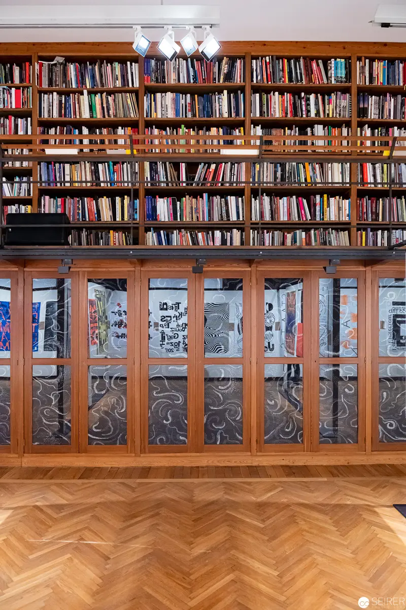 Expansive Library Interior with Herringbone Floor and Decorative Cabinets at MAK