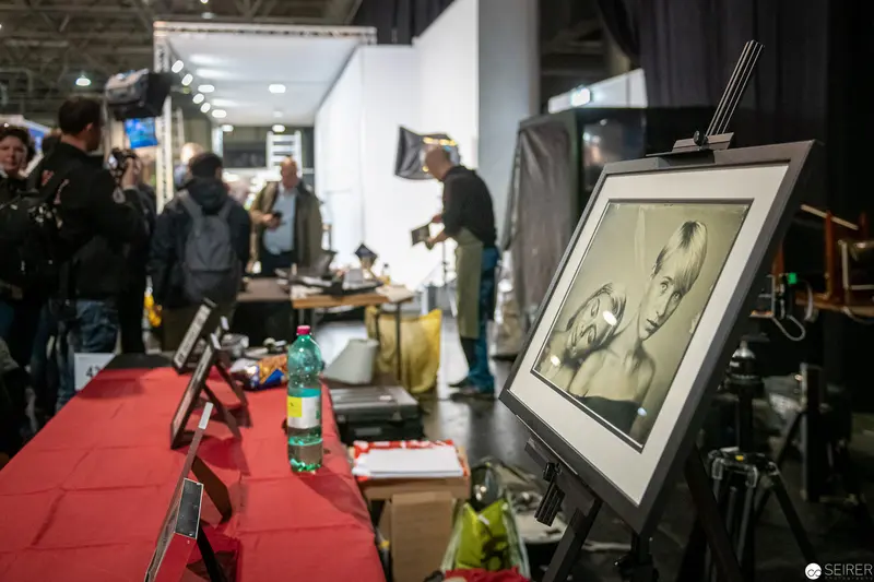 Art Exhibition Booth with Framed Portrait Sketch on Red-Draped Table