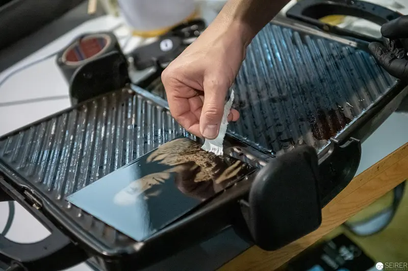 Close-Up of Hand Preparing Food on Ridged Grill Surface