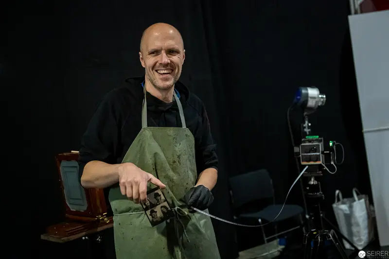 Artisan Craftsman in Green Apron Smiling at Workshop Station