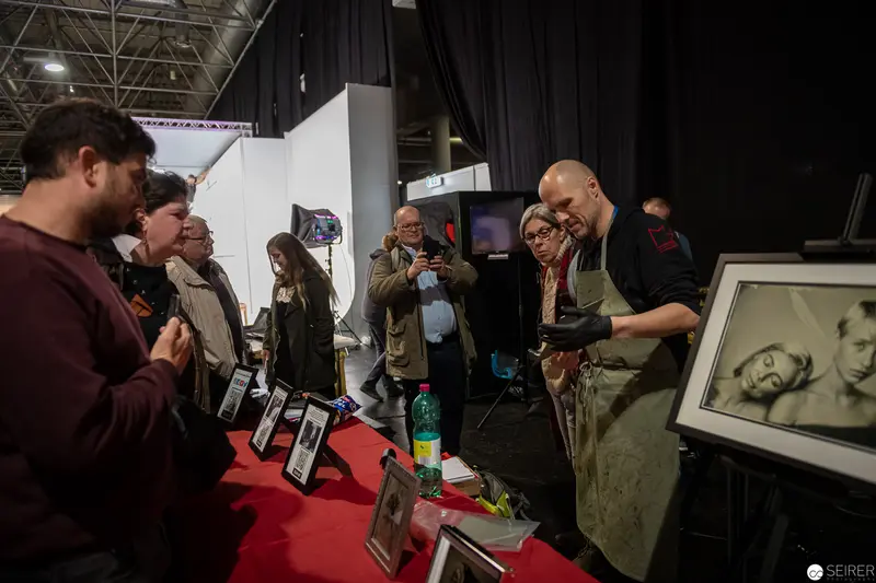 Art Exhibition Booth with Framed Photography and Engaged Audience Interaction