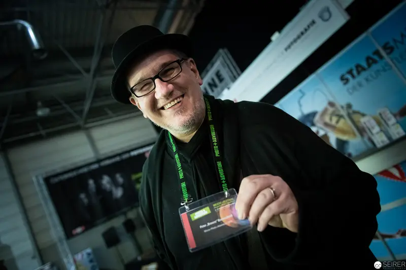 Smiling Conference Attendee with Lanyard in Industrial Setting