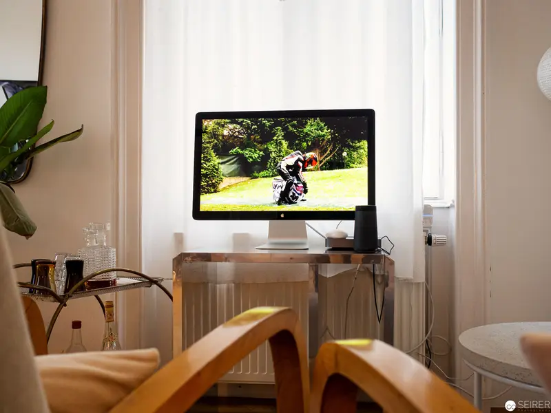 Domestic Interior with Computer Monitor Displaying Motorcycle Rider in Verdant Landscape