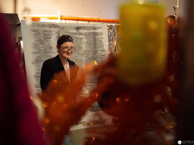 Artist in Contemplative Pose amid Blurred Autumnal Candle Installation