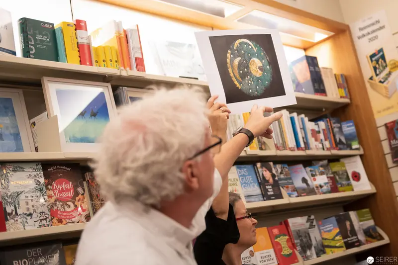 Visitor Examines Astronomical Print at Bookshop Display