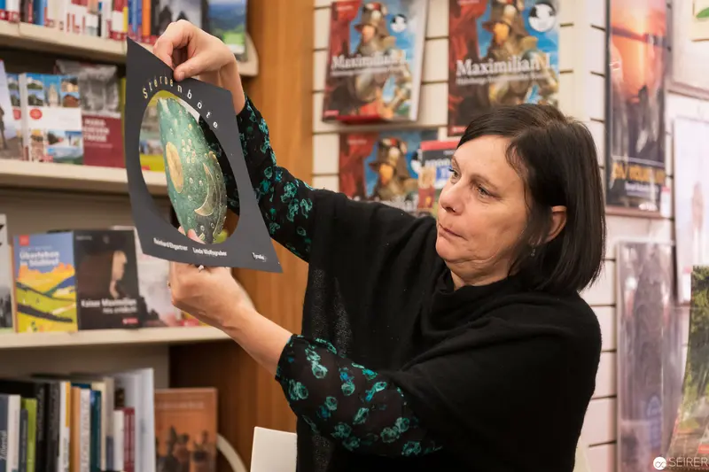 Woman Examining Illustrated Plate in Library Setting