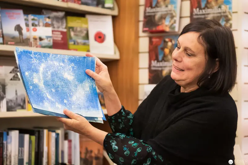 Woman Examining Blue Artwork in Library Setting