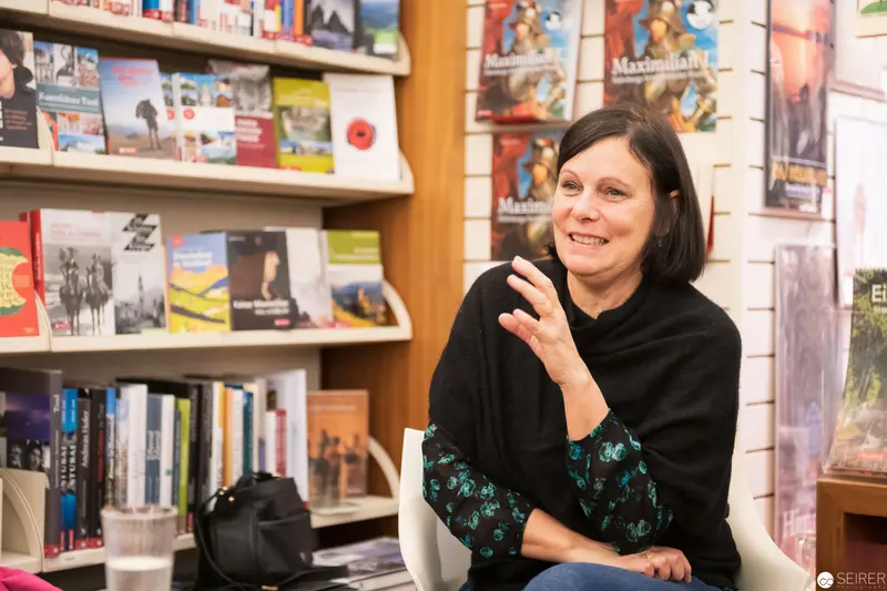 Woman Speaking in Library Setting with Books and Posters