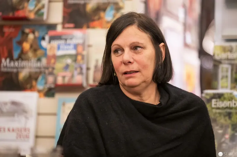 Woman Speaking at Gallery Event with Poster Displays