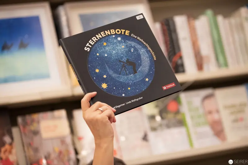 Person Holding "Sternenbote" Astronomy Book in Bookstore