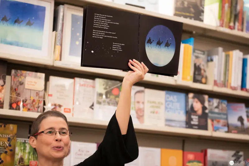 Young Reader Displaying Picture Book in Library Setting