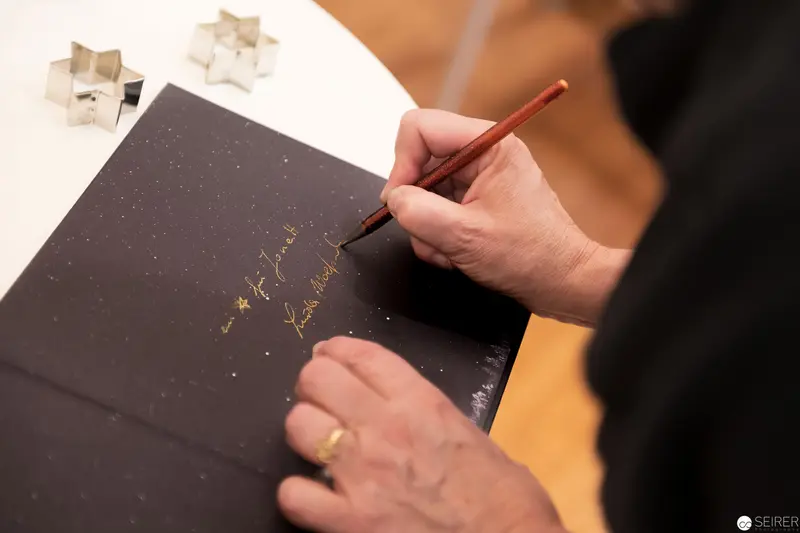 Calligrapher Writing Gold Script on Dark Paper with Wooden Stamps