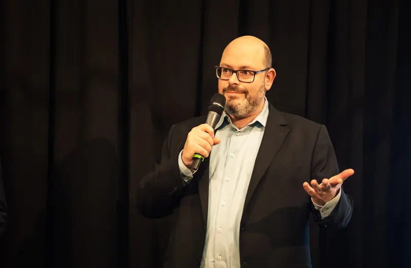 Bald Comedian Performing Standup Comedy with Microphone and Expressive Gesture