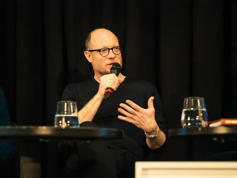Scholarly Speaker Gesturing during Panel Discussion in Black Attire