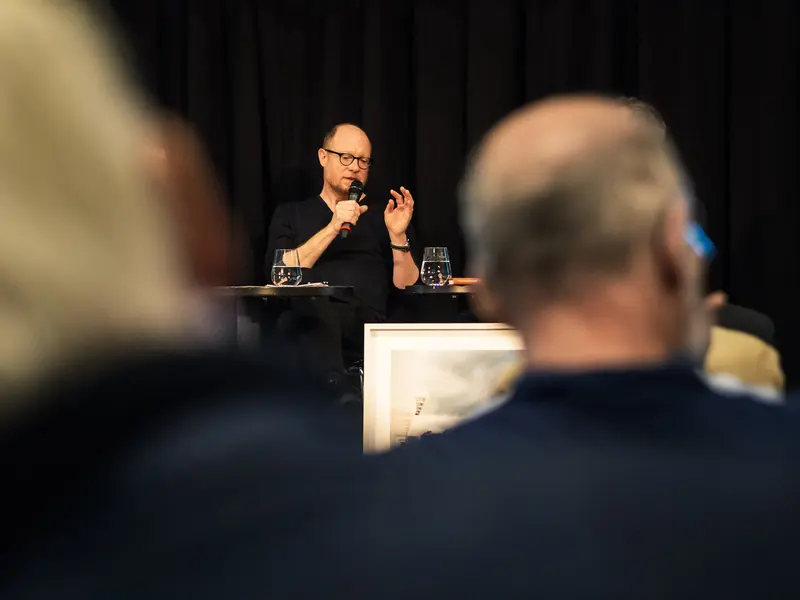 Lecturer Speaking at Conference with Microphone Against Dark Background