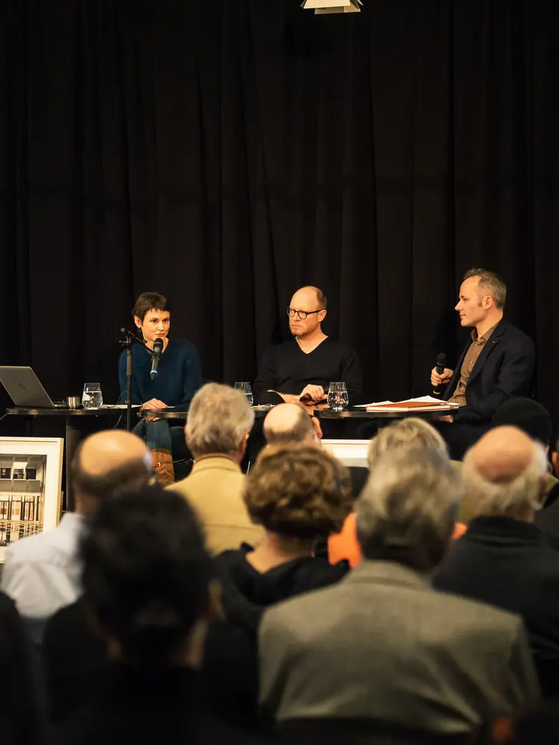 Panel Discussion with Three Speakers at Cultural Event Featuring Attentive Audience