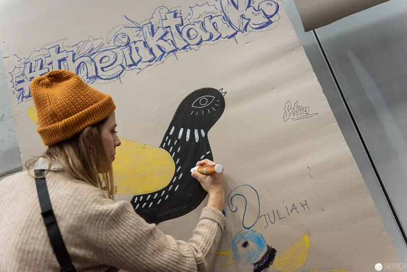 Artist in Yellow Beanie Drawing Stylized Comic Bird at Vienna ComicCon 2019
