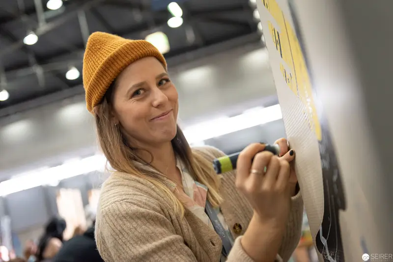 Woman in Mustard Beanie Annotating Presentation Board at VIECC 2019