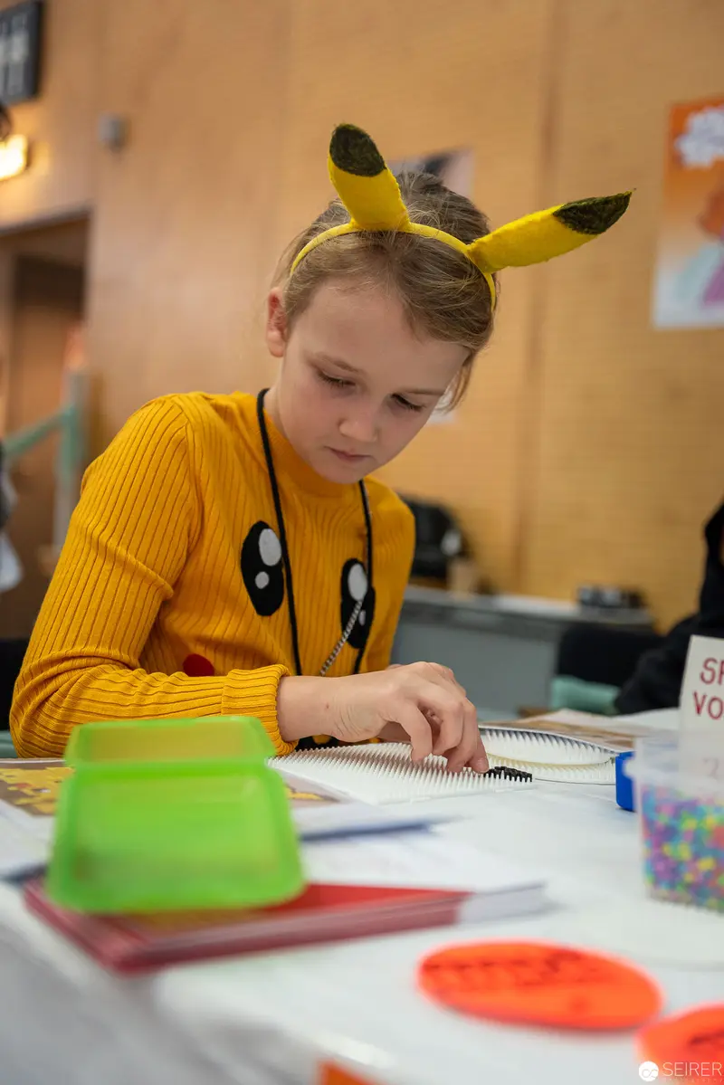 Young Student in Pikachu-Themed Attire Studying Intently at School Desk