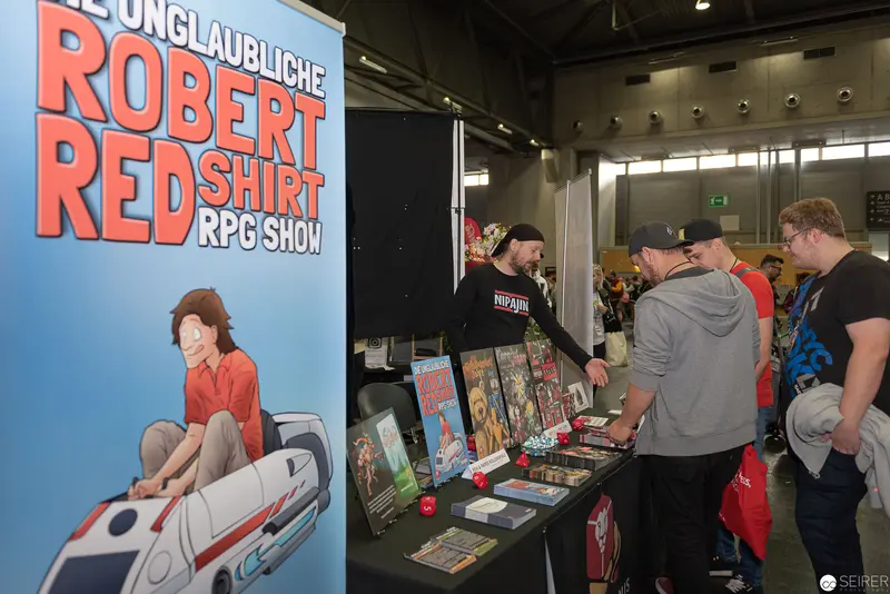 Robert Redshirt RPG Show Booth at Comic Convention Displaying Tabletop Gaming Materials