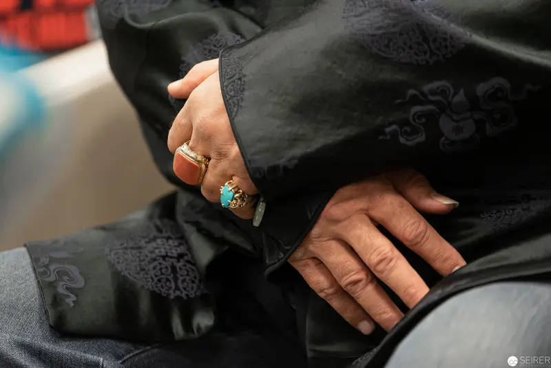Ornate Black Garment with Delicate Hands and Turquoise Ring