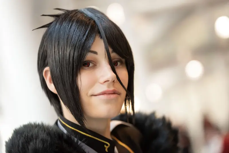 Cosplay Portrait at Vienna ComicCon 2019: Black-Haired Character in Feathered Costume