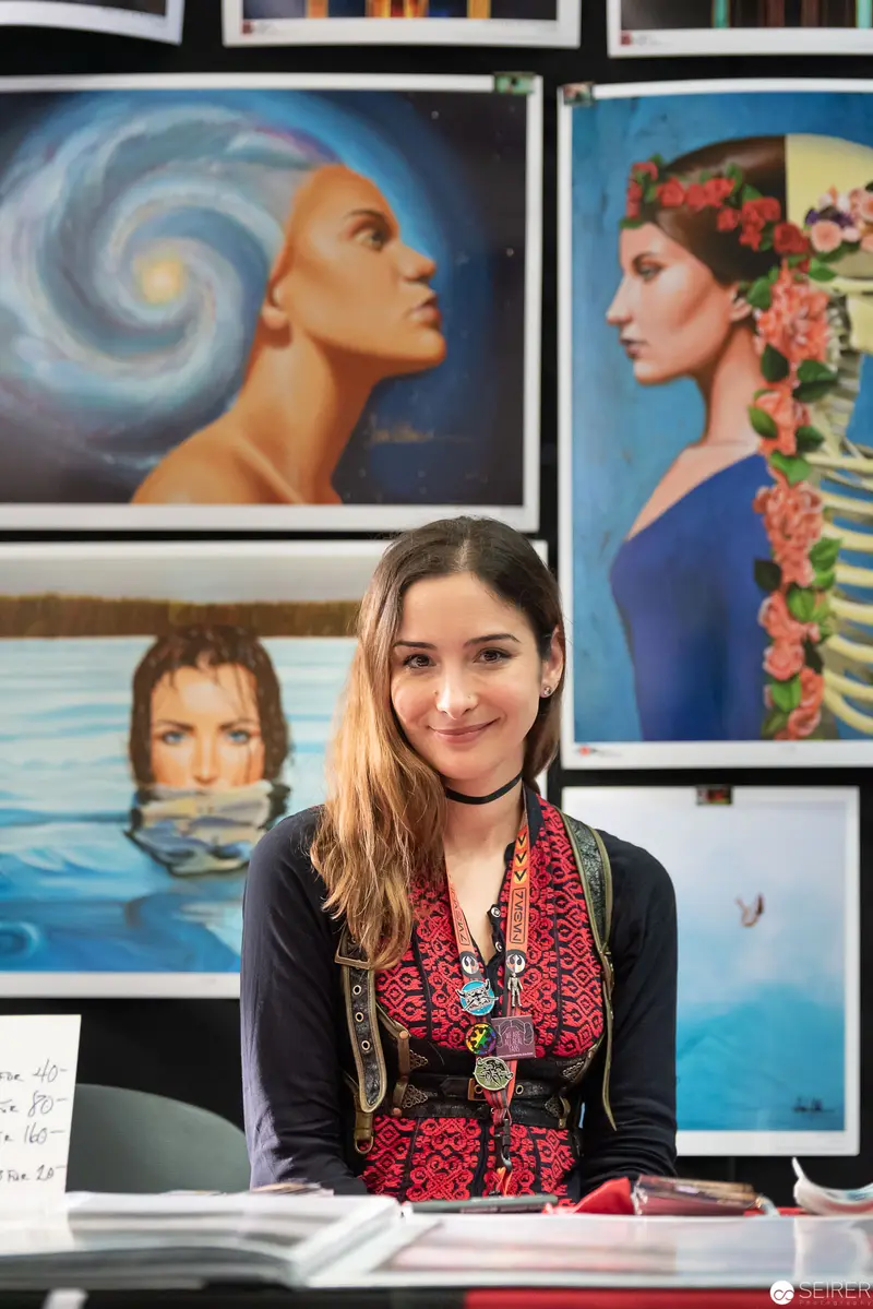 Artist Surrounded by Surreal Portraits at Personal Exhibition Space