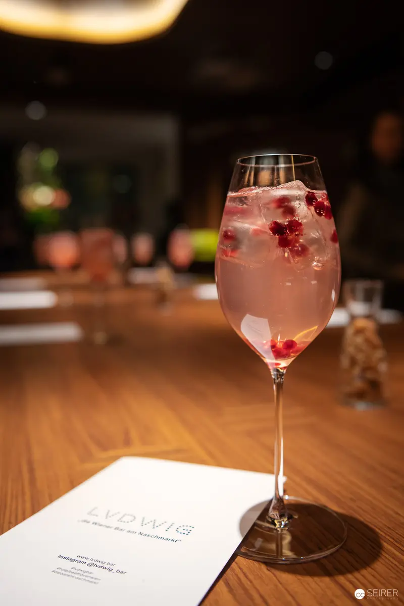 Artisanal Cocktail with Red Berries in Elegant Wine Glass on Wooden Surface