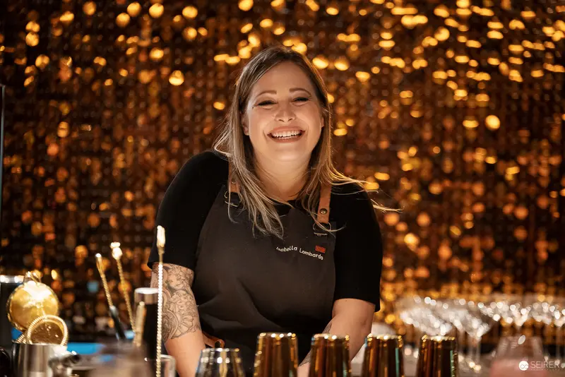 Smiling Bartender Preparing Cocktails Against Warm Golden Bokeh Background