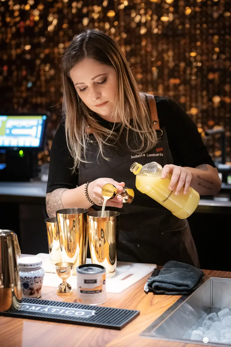 Bartender Crafting Cocktail with Precision at Golden-Lit Bar Station