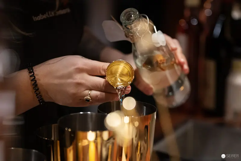Bartender Pouring Golden Liquor into Glassware During Precise Cocktail Preparation