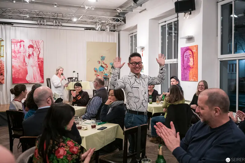 Art Gallery Event with Enthusiastic Speaker Amid Colorful Portraits
