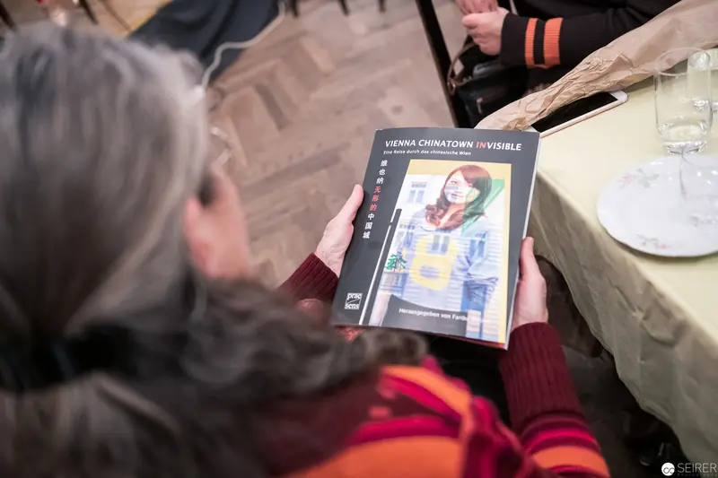 Reader Examining "Vienna Chinatown Invisible" Publication at Book Event