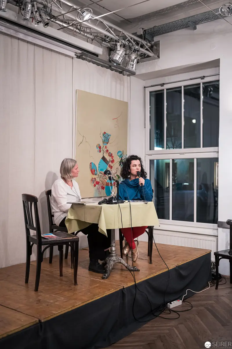 Intimate Performance on Small Stage with Artistic Backdrop and Audience Interaction