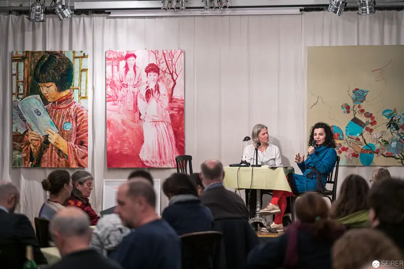 Art Panel Discussion with Vibrant Portraits Displayed Behind Speakers