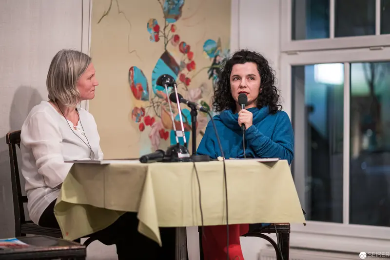 Panel Discussion on Stage with Two Women at Microphones