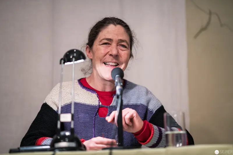 Public Speaker in Multicolored Sweater at Microphone Podium